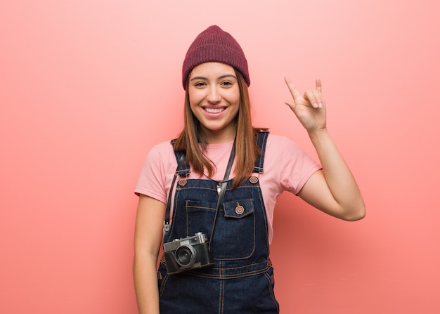 Giovane donna carina fotografo facendo un gesto rock