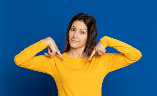 Giovane donna castana che gesturing sopra la parete blu