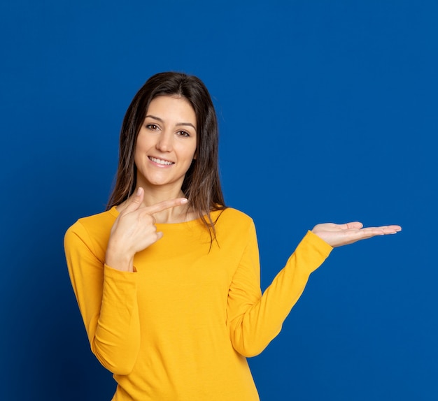 Giovane donna castana che gesturing sopra la parete blu