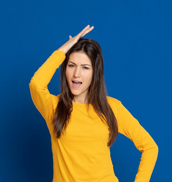 Giovane donna castana che gesturing sopra la parete blu