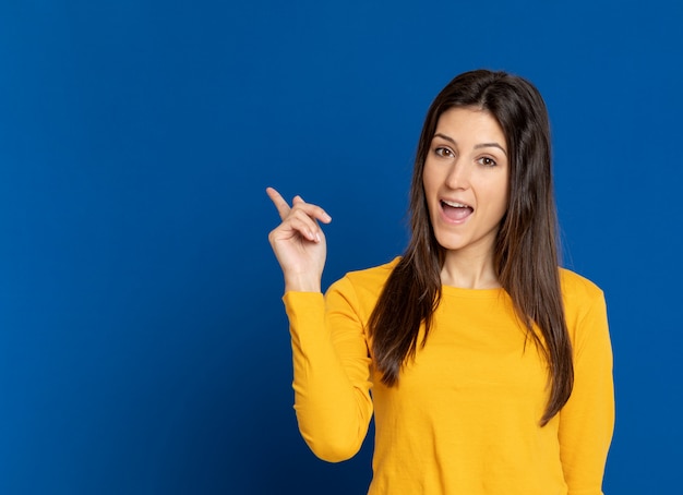 Giovane donna castana che gesturing sopra la parete blu