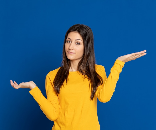 Giovane donna castana che gesturing sopra la parete blu