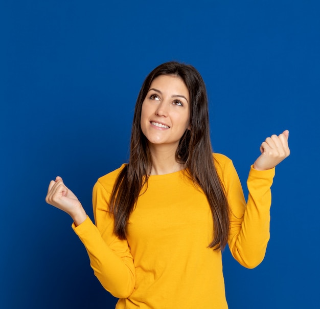 Giovane donna castana che gesturing sopra la parete blu