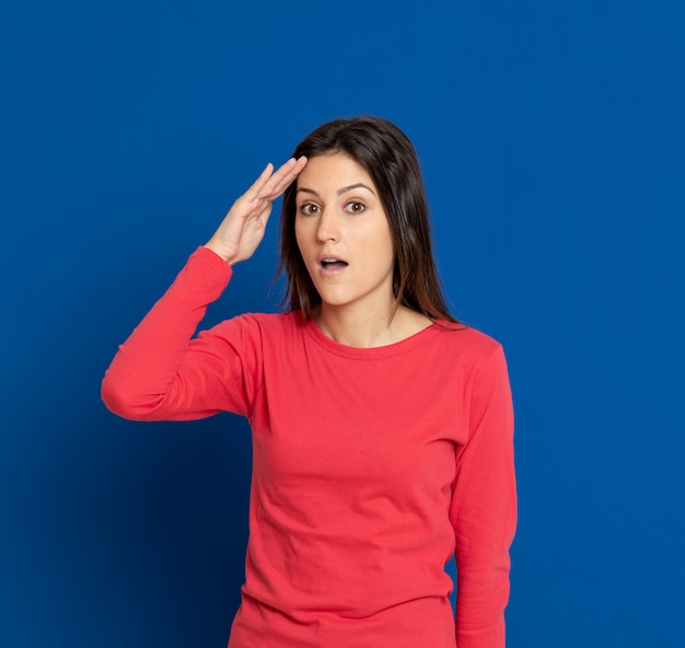 Giovane donna castana che gesturing sopra la parete blu