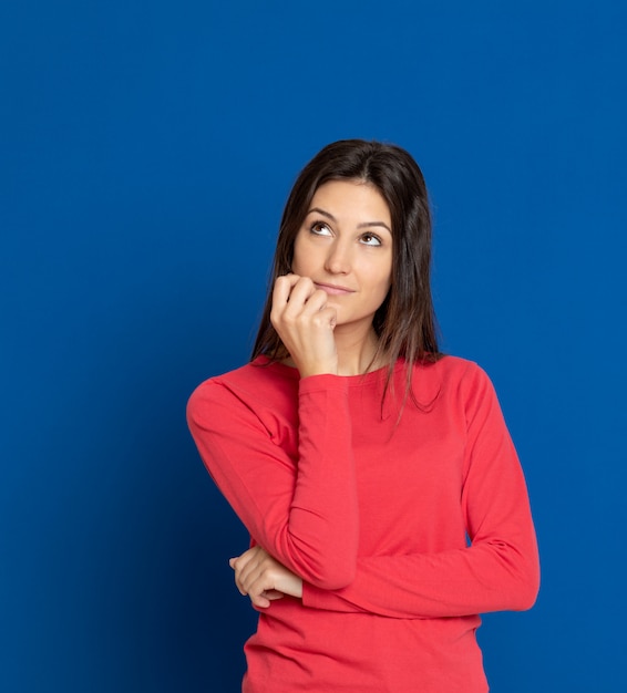 Giovane donna castana che gesturing sopra la parete blu