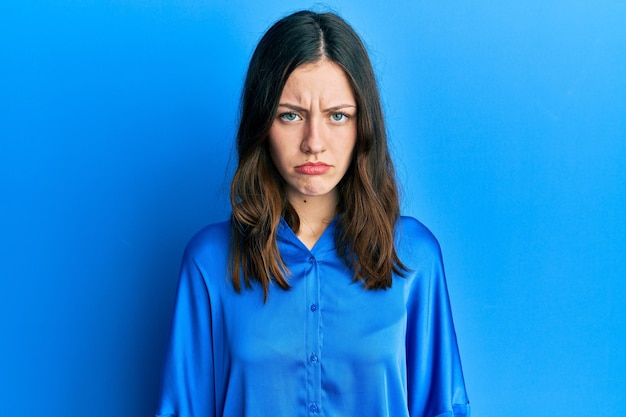 Giovane donna castana che indossa una camicia blu casual depressa e si preoccupa per l'angoscia piangendo un'espressione triste arrabbiata e impaurita