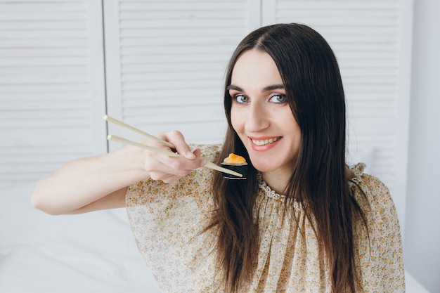 Giovane donna castana che mangia i sushi