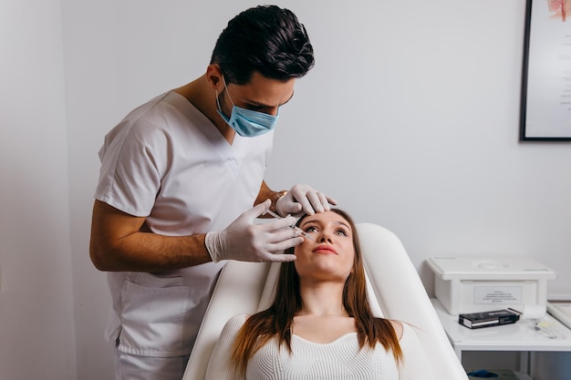 Giovane donna castana che riceve l'iniezione di chirurgia plastica sul viso