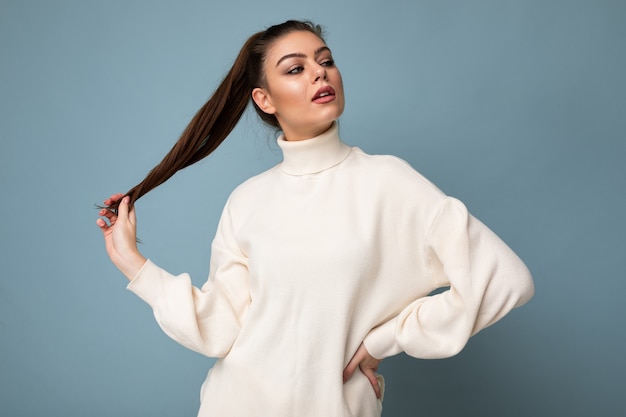 Giovane donna castana di modo caucasico sexy affascinante che indossa l'equilibrio bianco casuale del maglione