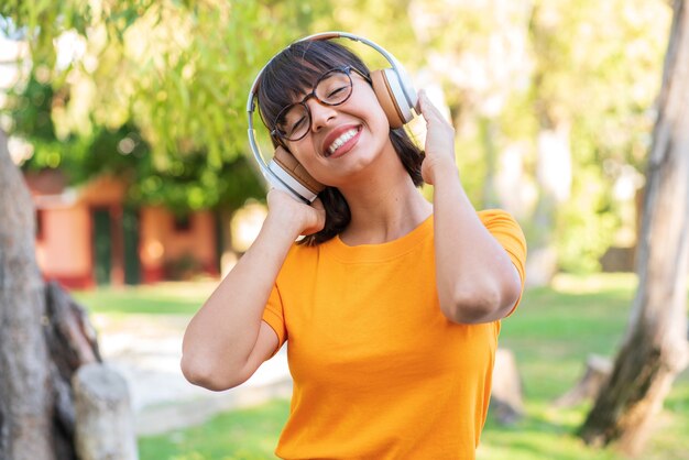 Giovane donna castana nel parco che ascolta musica