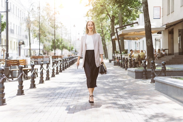 Giovane donna casual che cammina lungo una strada della città