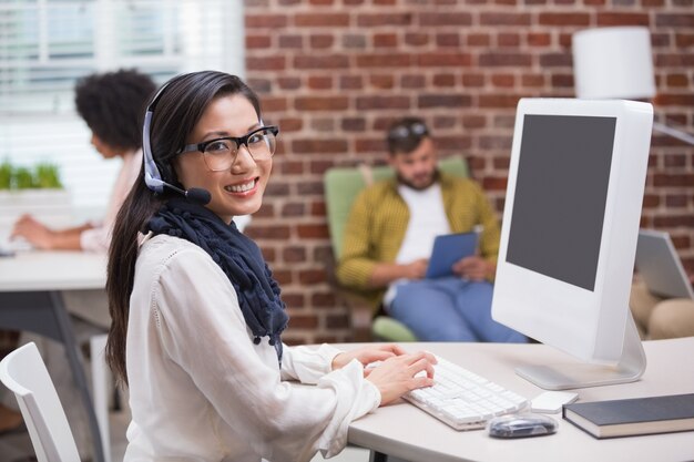 Giovane donna casuale sorridente che per mezzo del computer