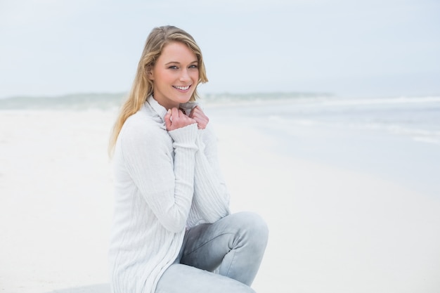 Giovane donna casuale sorridente che si distende alla spiaggia