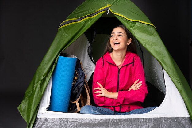 Giovane donna caucasica all'interno di una tenda da campeggio verde