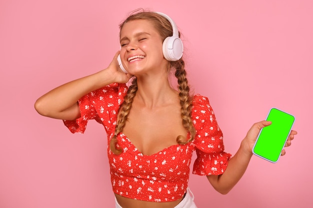 Giovane donna caucasica allegra che si diverte ad ascoltare musica con le cuffie