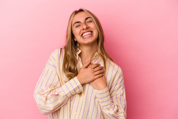 Giovane donna caucasica bionda che ride mantenendo le mani sul cuore, il concetto di felicità.