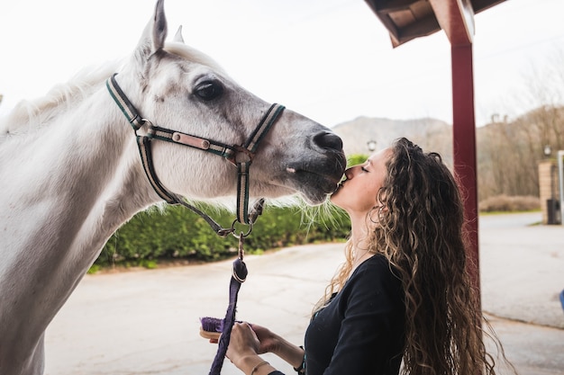 Giovane donna caucasica che bacia un cavallo