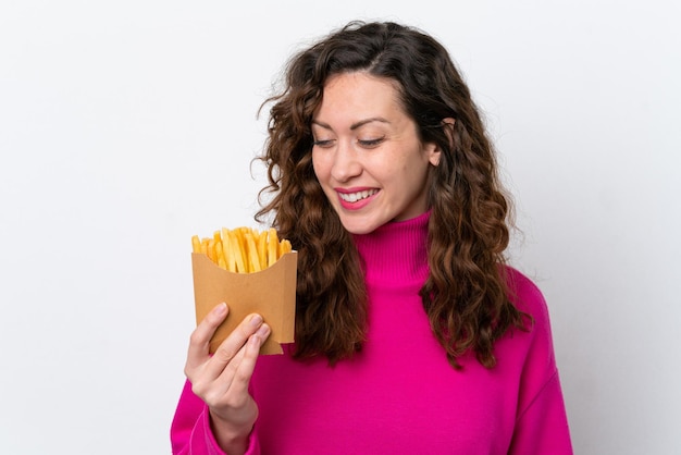 Giovane donna caucasica che cattura le patatine fritte isolate su priorità bassa bianca con l'espressione felice