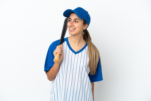 Giovane donna caucasica che gioca a baseball isolata guardando di lato e sorridente