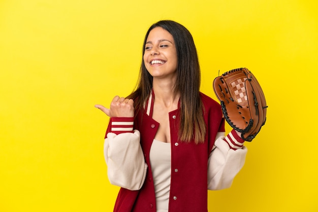 Giovane donna caucasica che gioca a baseball isolata su sfondo giallo che punta al lato per presentare un prodotto