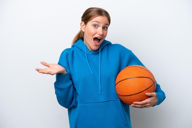 Giovane donna caucasica che gioca a basket isolata su sfondo bianco con espressione facciale scioccata