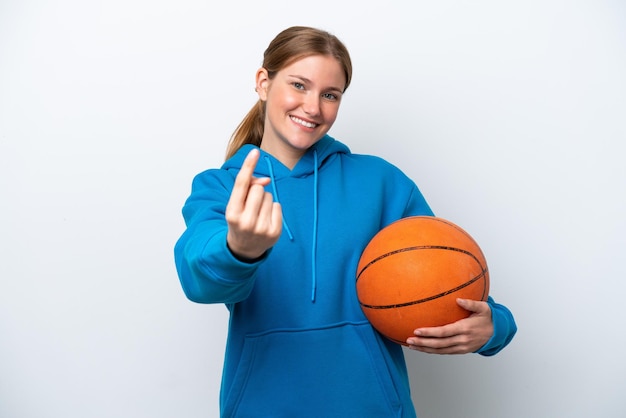 Giovane donna caucasica che gioca a basket isolata su sfondo bianco facendo il gesto in arrivo