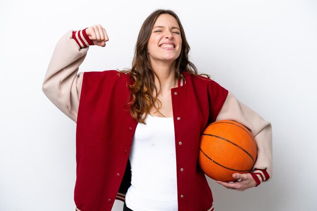 Giovane donna caucasica che gioca a basket isolata su sfondo bianco facendo un forte gesto