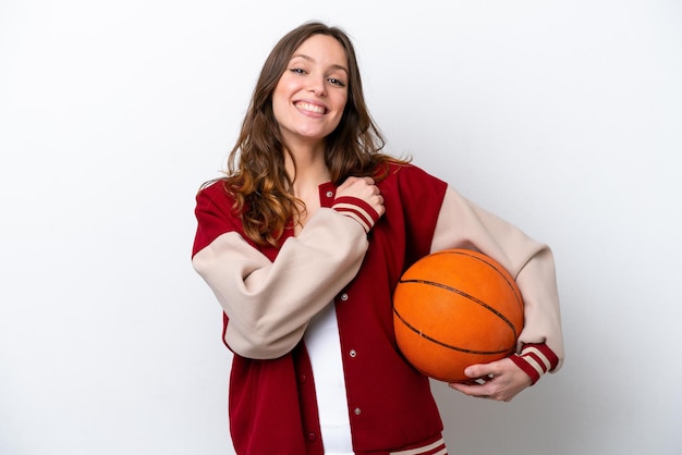 Giovane donna caucasica che gioca a basket isolato su sfondo bianco che celebra una vittoria