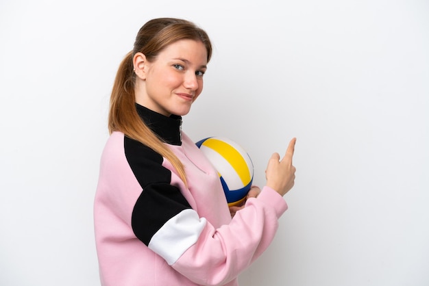 Giovane donna caucasica che gioca a pallavolo isolata su sfondo bianco che punta indietro