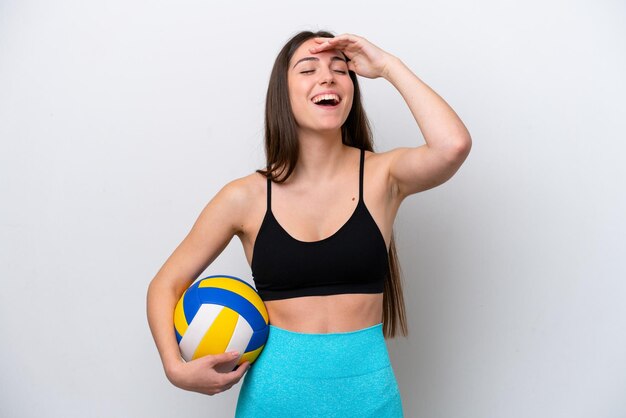 Giovane donna caucasica che gioca a pallavolo isolata su sfondo bianco che sorride molto