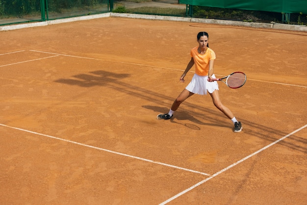Giovane donna caucasica che gioca a tennis al campo da tennis all'aperto.