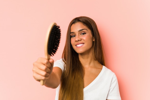 Giovane donna caucasica che giudica una spazzola per capelli isolata