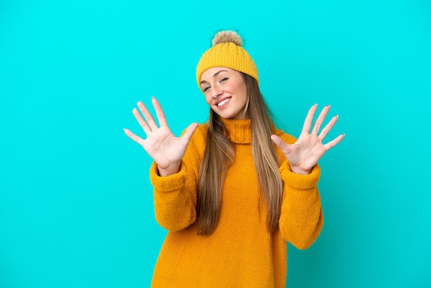 Giovane donna caucasica che indossa una giacca invernale isolata su sfondo blu contando dieci con le dita