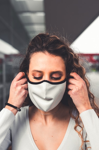 Giovane donna caucasica che indossa una maschera bianca in strada