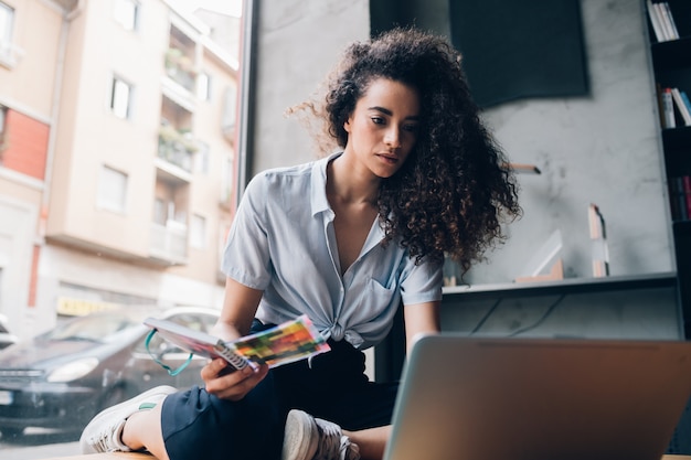 Giovane donna caucasica che lavora e che guarda computer portatile nello spazio coworking moderno