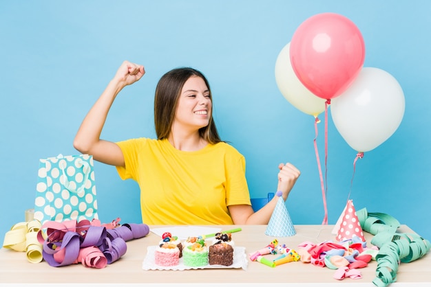 Giovane donna caucasica che organizza un compleanno che alza pugno dopo una vittoria, concetto del vincitore.