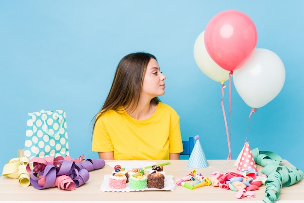 Giovane donna caucasica che organizza un compleanno che guarda a sinistra, posa laterale.