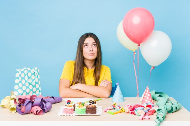 Giovane donna caucasica che organizza un compleanno stanco di un compito ripetitivo.