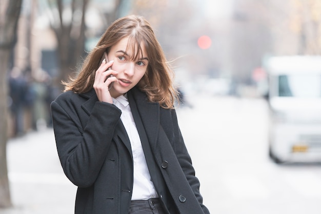 Giovane donna caucasica che parla con qualcuno con lo smartphone sull'orecchio