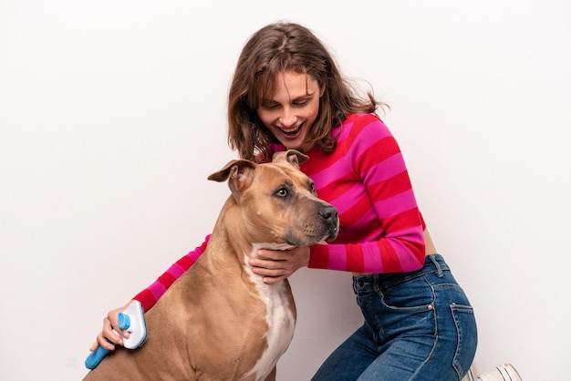 Giovane donna caucasica che pettina il suo cane isolato su priorità bassa bianca