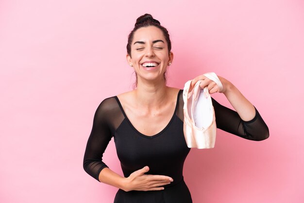 Giovane donna caucasica che pratica balletto isolato su sfondo rosa sorridente molto