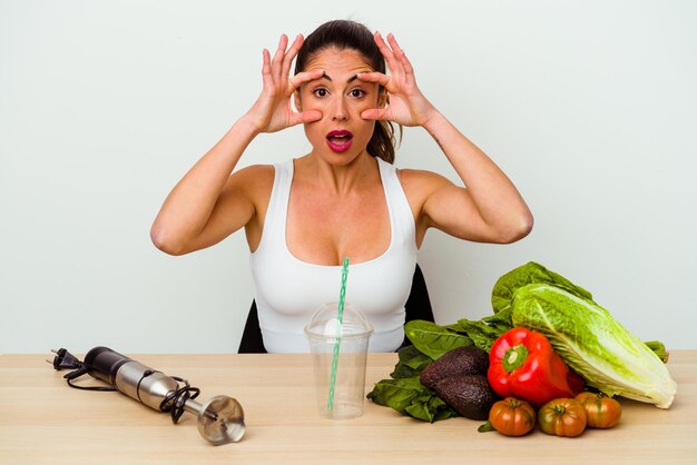 Giovane donna caucasica che prepara un frullato sano con le verdure