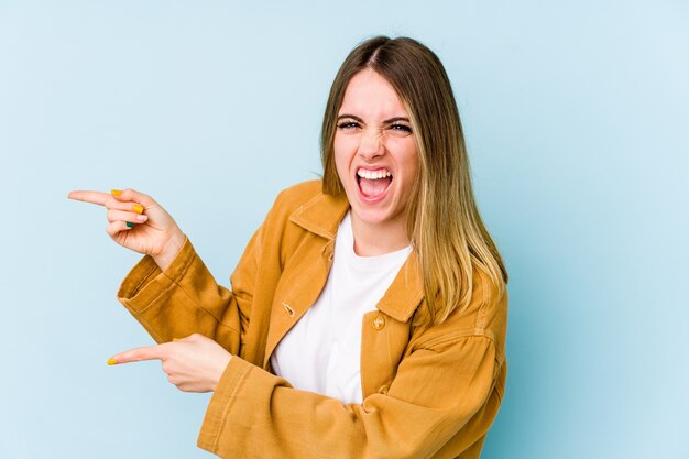 Giovane donna caucasica che punta con gli indici a uno spazio di copia, esprimendo eccitazione e desiderio.