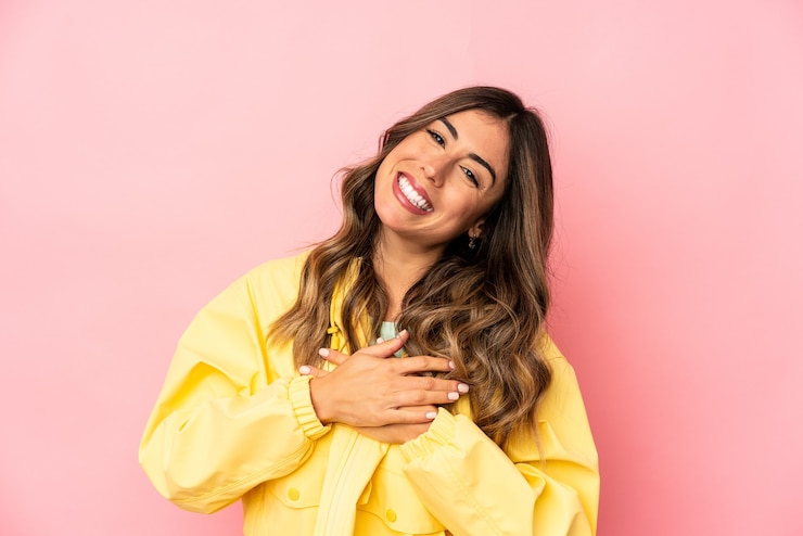Foto giovane donna caucasica che ride mantenendo le mani sul cuore, il concetto di felicità.