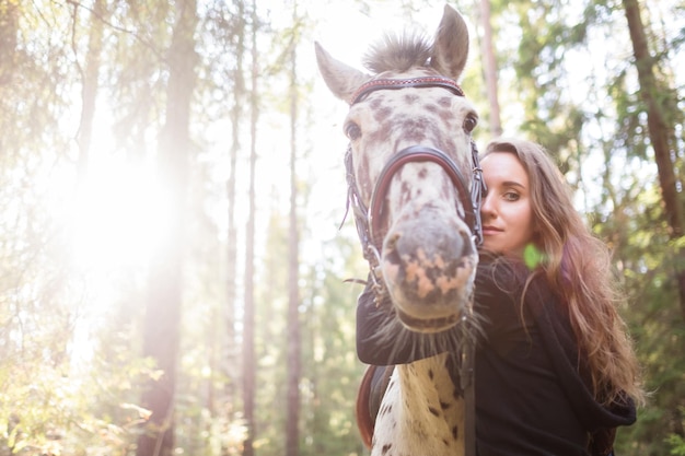 Giovane donna caucasica che si prende cura del suo cavallo che gli abbraccia il collo