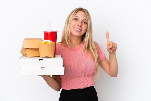 Giovane donna caucasica che tiene cibo grasso isolato su sfondo blu che indica una grande idea