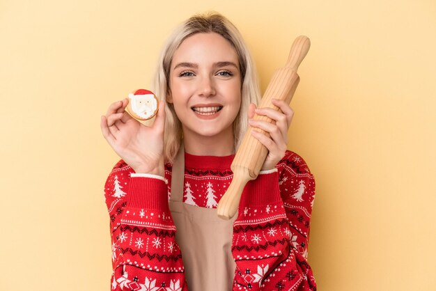 Giovane donna caucasica che tiene i biscotti di Natale isolati su sfondo giallo