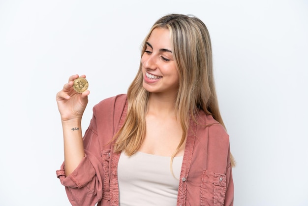 Giovane donna caucasica che tiene un Bitcoin isolato su sfondo bianco con felice espressione