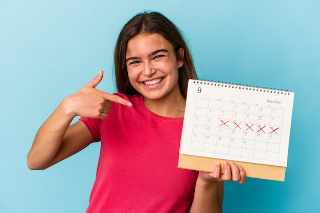 Giovane donna caucasica che tiene un calendario isolato su sfondo blu