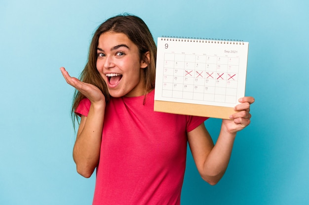 Giovane donna caucasica che tiene un calendario isolato su sfondo blu